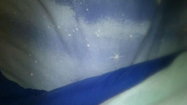 Eine Textilie mit Blutflecken liegt gefaltet auf einem blauen und einem gr&uuml;nen Stoff im Hintergrund.