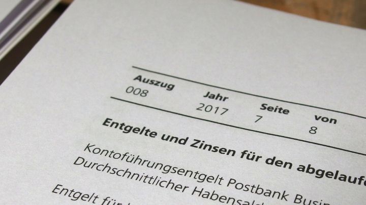 Ein Dokument zeigt Informationen &uuml;ber Kontof&uuml;hrungsgeb&uuml;hren und Zinsen, datiert auf 2017, in einem B&uuml;ro-Setting.