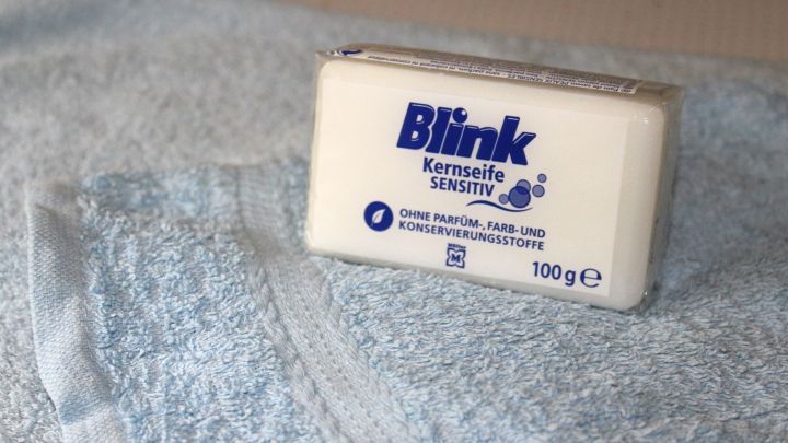 Eine wei&szlig;e Kernseife liegt auf einem blauen Handtuch, bereit zur Verwendung gegen Pickel.