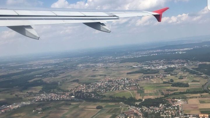 Blick aus dem Flugzeug auf eine gr&uuml;ne Landschaft mit D&ouml;rfern und Feldern, w&auml;hrend man durch getrocknete Kirschen entspannt.