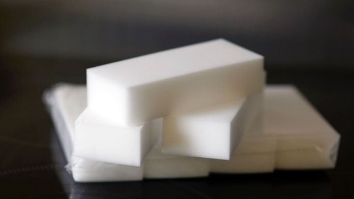 Eine Glaskeramikplatte wird mit einem Schmutzradierer gereinigt, um Flecken zu entfernen. Der Hintergrund ist eine dunkle Oberfl&auml;che.