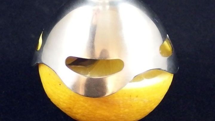 Ein Zitruspressenaufsatz hebt sich &uuml;ber einer frisch geschnittenen Zitrone, um Saft in eine Sch&uuml;ssel zu pressen.