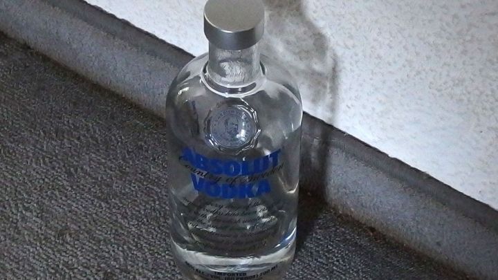 Eine Flasche klaren Wodkas steht auf dem Boden und deutet darauf hin, dass sie m&ouml;glicherweise zur Abhaltung von Katzen vom Pinkeln verwendet wird.