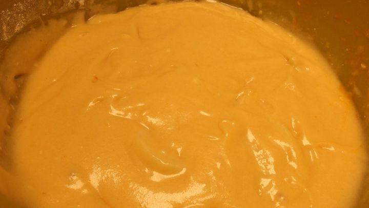 Eine goldene, glatte R&uuml;hrteigmasse ruht in einer Sch&uuml;ssel, bereit f&uuml;r das Backen in einer warmen K&uuml;che.