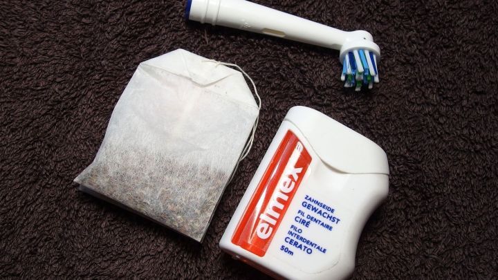 Zahnb&uuml;rste und Zahnpasta liegen neben einem Teebeutel auf einem dunklen Untergrund, um gesunde Z&auml;hne zu f&ouml;rdern und Karies zu verhindern.