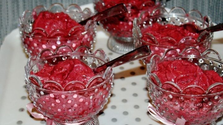 Rote Fruchteisportionen stehen auf einem Teller, umgeben von einer dottierten Oberfl&auml;che, ideal f&uuml;r warme Tage.