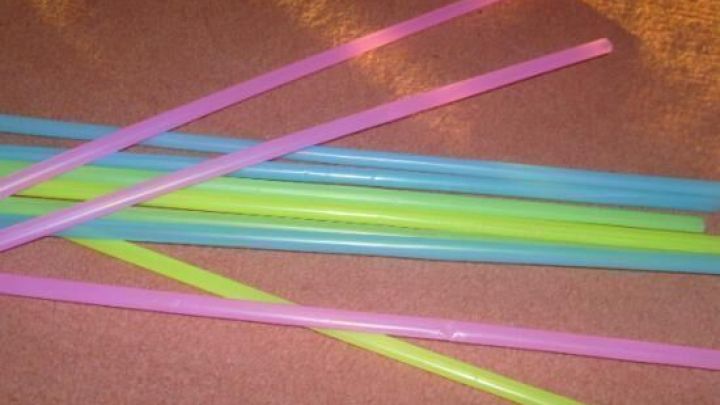 Bunte Plastiktrinkhalme liegen verstreut auf einem orangefarbenen Teppichboden.