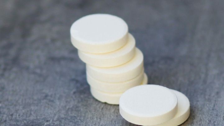 Wei&szlig;e, runde Tabletten liegen gestapelt auf einer grauen Oberfl&auml;che, die zur schnellen Linderung von Herpes verwendet werden k&ouml;nnen.