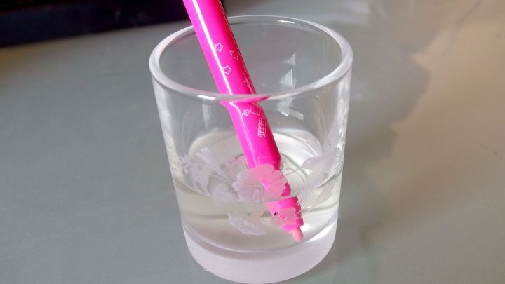 Ein pinker Filzstift steckt in einem Glas mit Essig, um eingetrocknete Tinte zu l&ouml;sen. Der Hintergrund ist neutral.