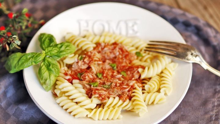 Eine wei&szlig;e Schale mit Fusilli-Nudeln, belegt mit Thunfisch in italienischer Tomatensauce und frischem Basilikum.