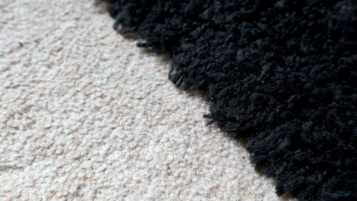 Eine schwarze Teppichkante st&ouml;&szlig;t auf einen beige Teppich, deutlich unterschiedliche Strukturen, nebeneinanderliegend.