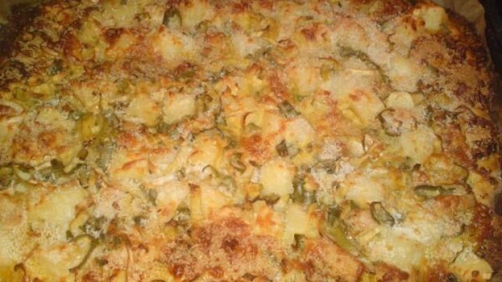 Eine Pizza mit karibischen Zutaten wie Ananas und gr&uuml;nen Paprika ist gebacken und goldbraun in einem hei&szlig;en Ofen.