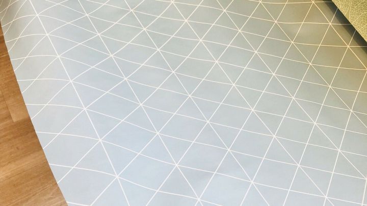 Ein handgehaltenes Wachstuch mit einem geometrischen Muster wird bereitgelegt, um eine K&uuml;chenausstattung ansprechend zu gestalten.