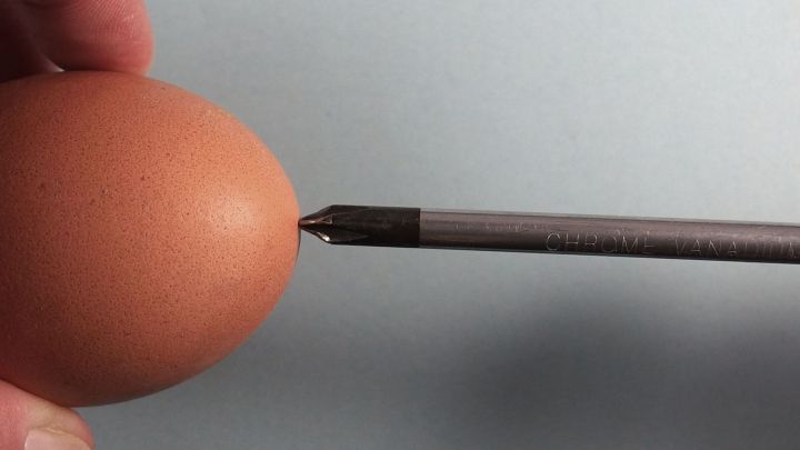 Ein Hand h&auml;lt ein Ei, w&auml;hrend ein Werkzeug daf&uuml;r verwendet wird, um ein (Oster)-Ei auszublasen.