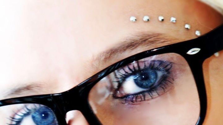 Eine Person mit modischer Brille und auff&auml;lliger Gesichtsbemalung schaut direkt in die Kamera, um Klarheit zu symbolisieren.