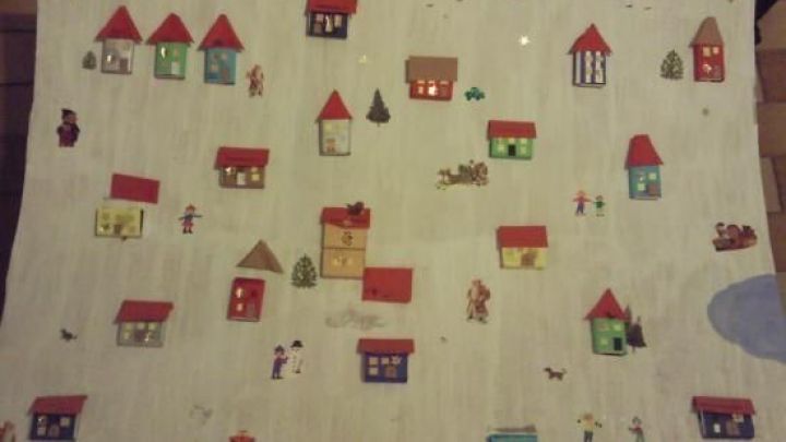 Bunte Papierh&auml;user und Weihnachtsb&auml;ume zieren einen Adventskalender, der f&uuml;r kleinere Kinder gestaltet ist.
