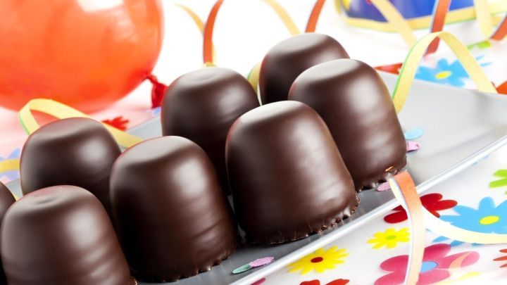 Schokok&uuml;sse stehen auf einem Tablett, dekoriert mit bunten Luftschlangen, vor Luftballons auf einem Kindergeburtstag.