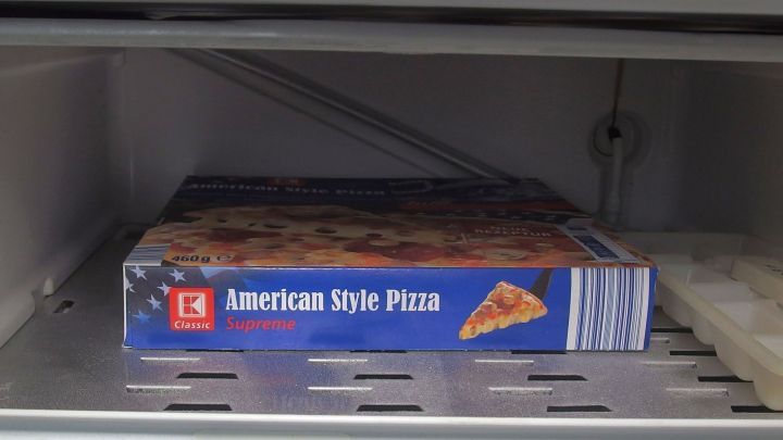 Eine tiefgek&uuml;hlte American Style Pizza liegt im Eisfach, um frisch zu bleiben und f&uuml;r die Zubereitung bereit zu sein.