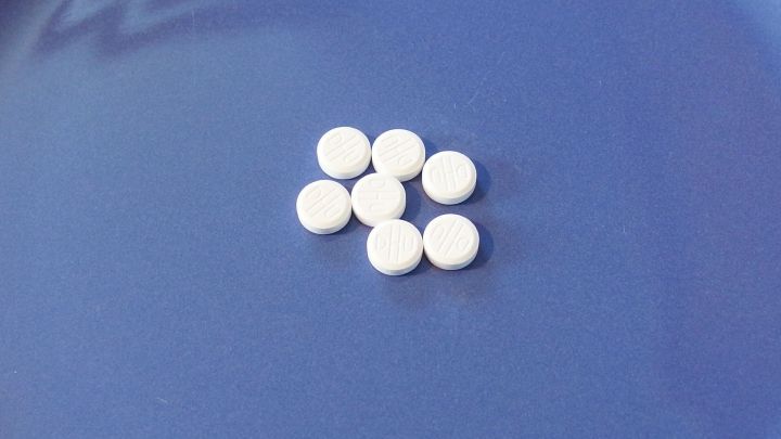 Sechs kleine wei&szlig;e Tabletten liegen auf einem blauen Untergrund und deuten auf die Verwendung von Sch&uuml;&szlig;ler-Salzen gegen unreine Haut hin.