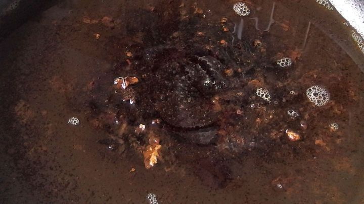 Ein angebrannter Kochtopf mit Wasser und Sp&uuml;lmittel steht auf einer Kochplatte und zeigt Reste von verbranntem Essen.