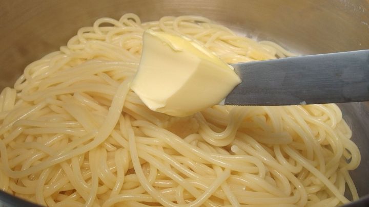 Nudeln werden mit einem St&uuml;ck Butter in einem Topf vermengt, um ein Ankleben zu verhindern und Geschmack zu verleihen.
