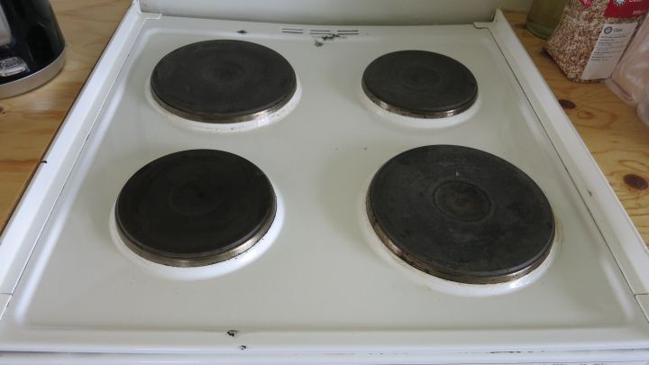 Herdplatten glänzen in Schwarz, während sie auf einem weißen Herd montiert sind, umgeben von einer neutralen Holzoberfläche.