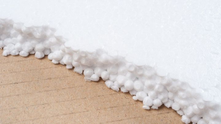 Wei&szlig;er Styroporreste befinden sich an der Kante eines Holzuntergrunds und k&ouml;nnten in die Blumenerde gemischt werden.