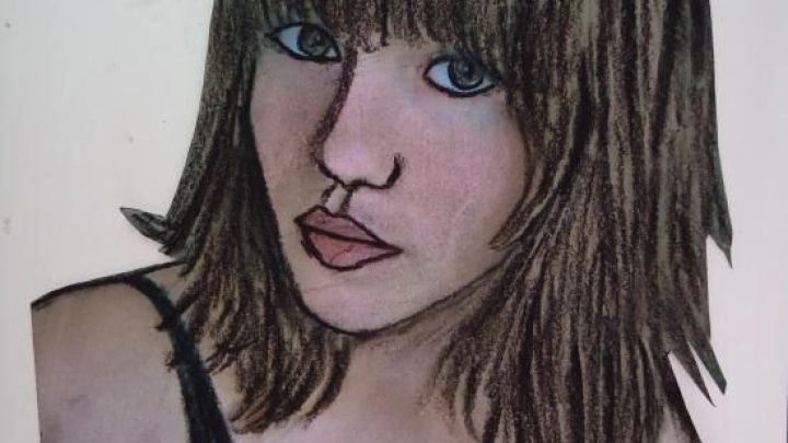 Ein Portr&auml;t einer jungen Frau mit langen, braunen Haaren, die mit Kohlestift lebhaft in einer schwarzen Bluse dargestellt ist.