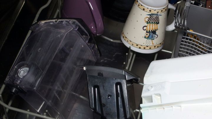 Eine Sp&uuml;lmaschine mit teilweise unvoller Beladung zeigt verschiedene Tassen und Ger&auml;teteile, die sauber gewaschen werden sollen.