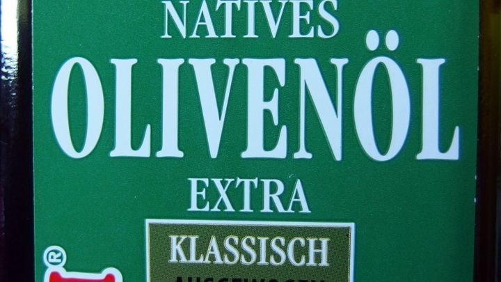 Eine Flasche natives Oliven&ouml;l steht im Vordergrund, beschriftet mit &bdquo;Klassisch Ausgewogen&ldquo;, umgeben von einer neutralen Umgebung.