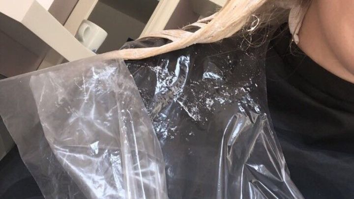 Eine Person tr&auml;gt eine Schutzblende aus Plastik w&auml;hrend der Anwendung einer Silberglanzsp&uuml;lung gegen Gelbstich am Haar in einem Salon.