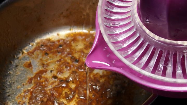 Edelstahltopf mit angebrannten Resten wird mit einem Zitronensaft-Squeezer gereinigt, um R&uuml;ckst&auml;nde zu entfernen.