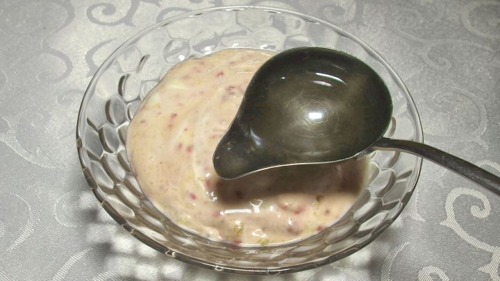 Cremeartige Quarkspeise wird mit einem silbernen L&ouml;ffel aus einer dekorativen Sch&uuml;ssel serviert, auf einem eleganten Tisch.