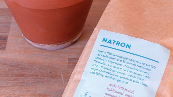 Ein Tontopf steht auf einer Holzoberfl&auml;che, daneben liegt eine T&uuml;te mit Natron, das zur Entfernung von Kalkresten verwendet wird.