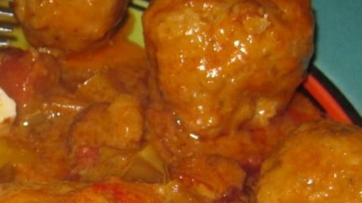 Scharfe B&auml;llchen in einer w&uuml;rzigen Sauce liegen auf einem bunten Teller, umgeben von frischem Gem&uuml;se.