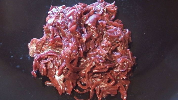 Rote Zwiebeln liegen in einer tiefen Sch&uuml;ssel, bereit zum W&uuml;rzen f&uuml;r die Zubereitung von Rotkohl.