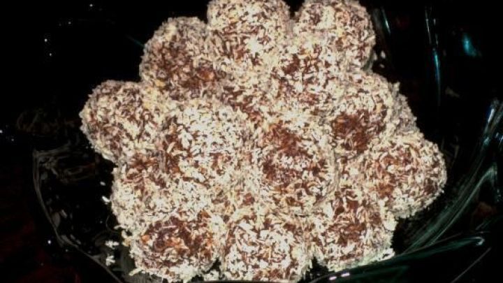 Kokos-B&auml;llchen liegen dekorativ auf einem Tisch in einer Schale und sind mit Kokosflocken bedeckt.