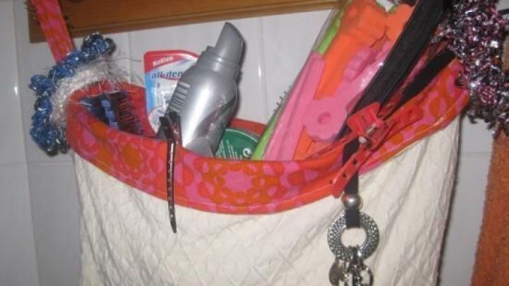 Eine h&auml;ngende Tasche am Regal h&auml;lt verschiedene Pflegeprodukte und Utensilien, in einem hellen Badezimmer platziert.