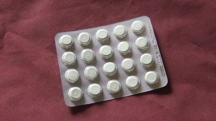 Eine Blisterpackung mit Tabletten liegt auf einem roten Untergrund, bereit zur Einnahme, um das Vergessen zu vermeiden.