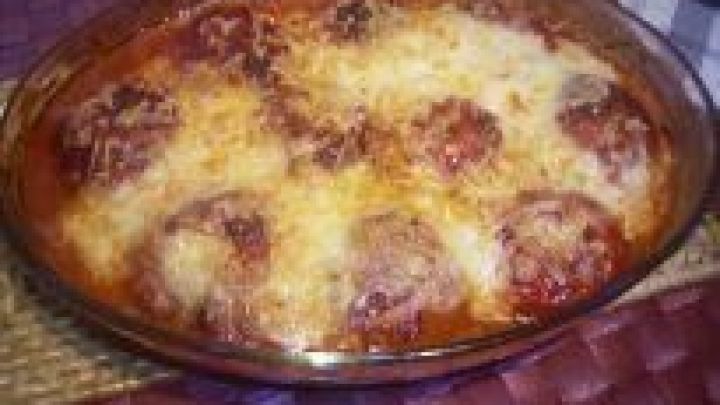 Ein Tomaten-Hack-Auflauf mit K&auml;se &uuml;berbacken befindet sich in einer Glasauflaufform auf einem geflochtenen Platzdeckchen.