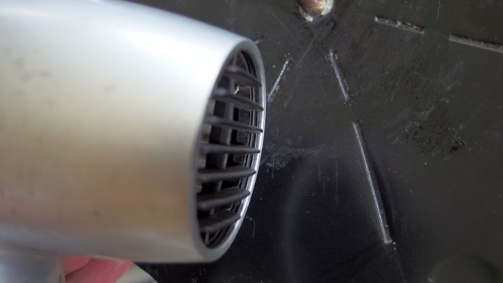 Ein Haartrockner wird verwendet, um Kerzenreste von einem Kerzenst&auml;nder zu entfernen. Der St&auml;nder ist schwarz.