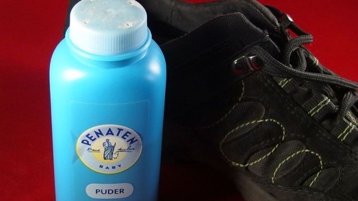 Ein blauer Puderbeh&auml;lter steht neben einem Schuh, um quietschenden Schuhen in einem roten Umfeld Abhilfe zu schaffen.
