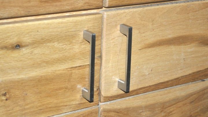 Holzm&ouml;bel mit gl&auml;nzenden Metallgriffen in Nahaufnahme, ruhig und detailreich in hellem Innenraum positioniert.