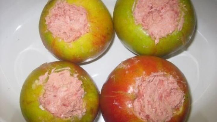 Gr&uuml;ne und rote &Auml;pfel stehen in einer Sch&uuml;ssel und sind mit einer pinken Fleischf&uuml;llung gef&uuml;llt, bereit zum Backen.