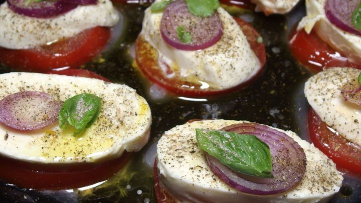 Tomaten und Mozzarella scheinen in einem Gericht zubereitet zu werden, garniert mit frischen Kr&auml;utern und Gew&uuml;rzen.