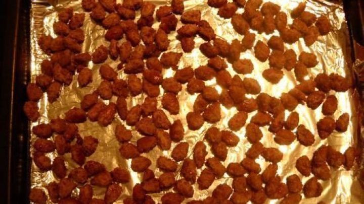 Die gebrannten Thymian-Mandeln liegen auf einem Backblech mit Folie, gleichm&auml;&szlig;ig verteilt und knusprig.