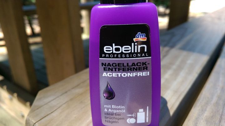 Ein lila Nagellackentferner steht auf einem Holzuntergrund, bereit, um Pinienharz vom Auto zu entfernen.