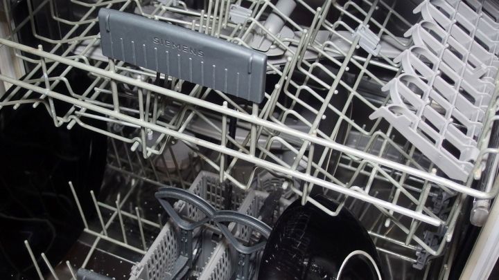 Ein Sp&uuml;lmaschine ist gef&uuml;llt mit schmutzigem Geschirr, w&auml;hrend das saubere Geschirr zum Trocknen bereitsteht.