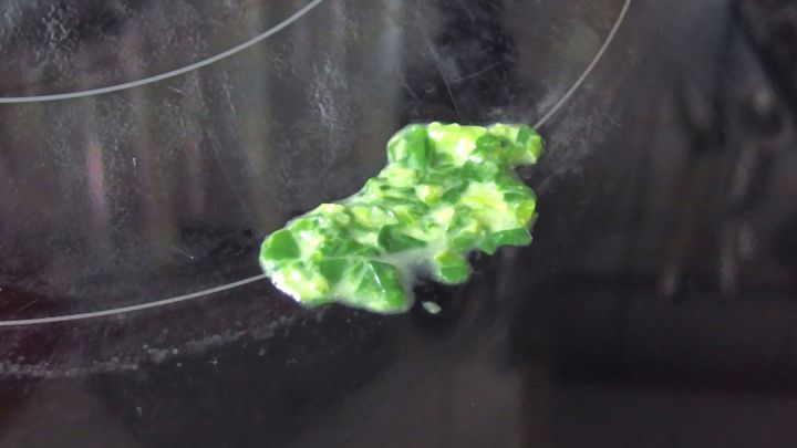 Auf dem Herd liegt eine eingetrocknete Kruste, die mit einem Reinigungsmittel bearbeitet wird, um sie zu l&ouml;sen.