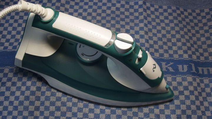 Ein Dampfb&uuml;geleisen steht auf einem geb&uuml;gelten, karierten Stoff und wartet darauf, verwendet zu werden.